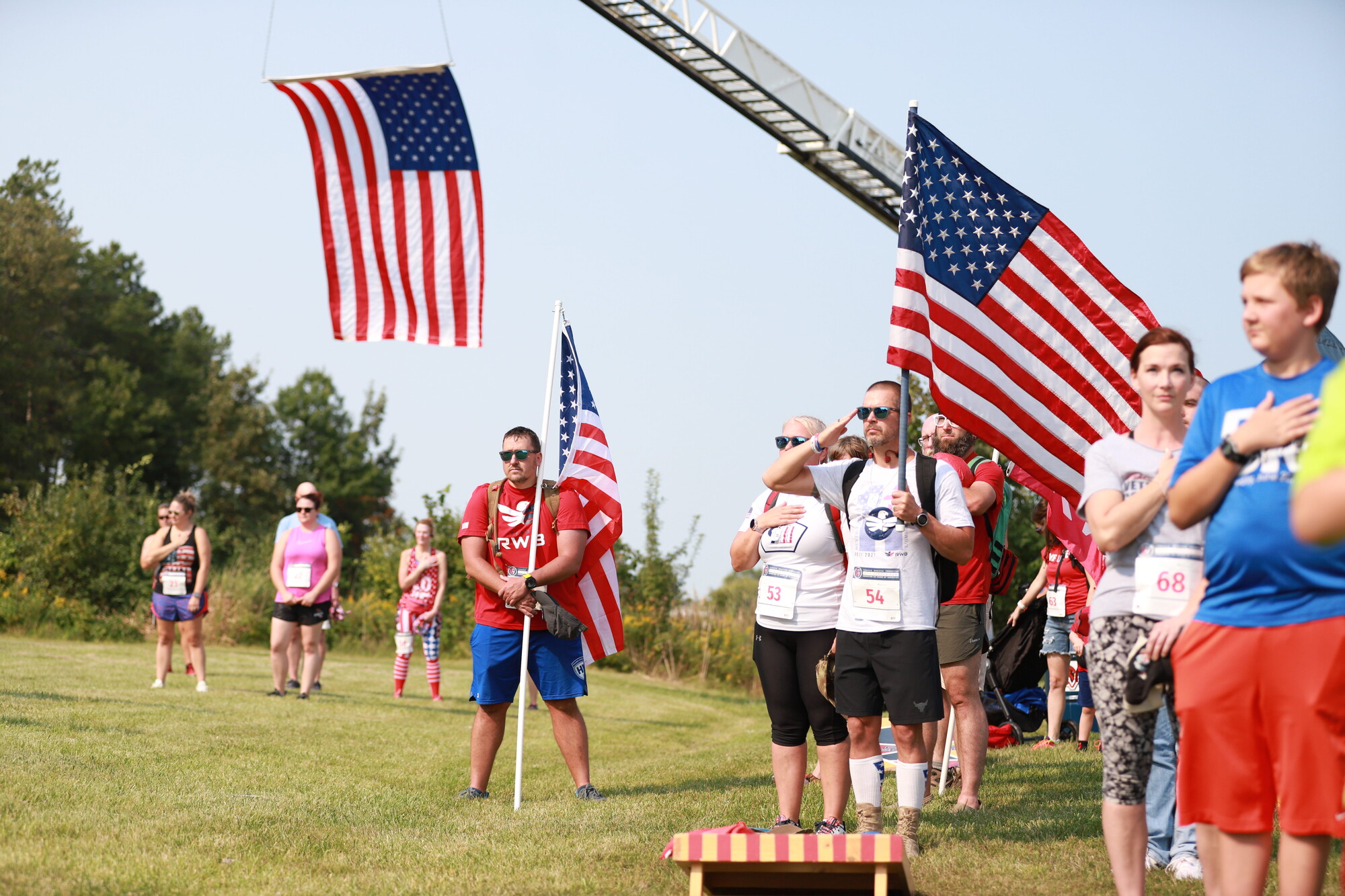 People standing with hands on hearts, American flags in frame